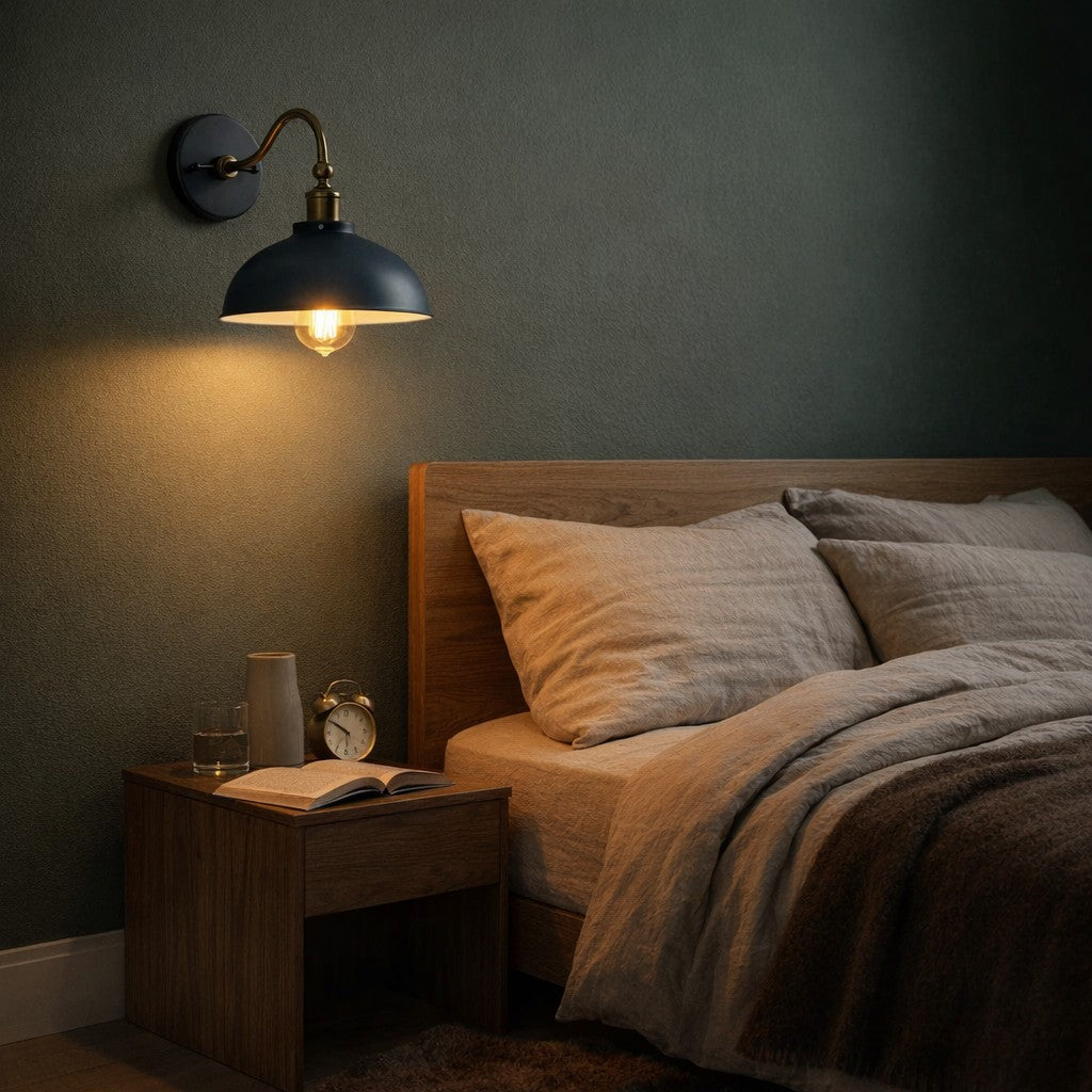 Aldgate adjustable industrial dome wall sconce in deep blue, mounted beside an oak headboard against a sage-green bedroom wall, glowing warm at night