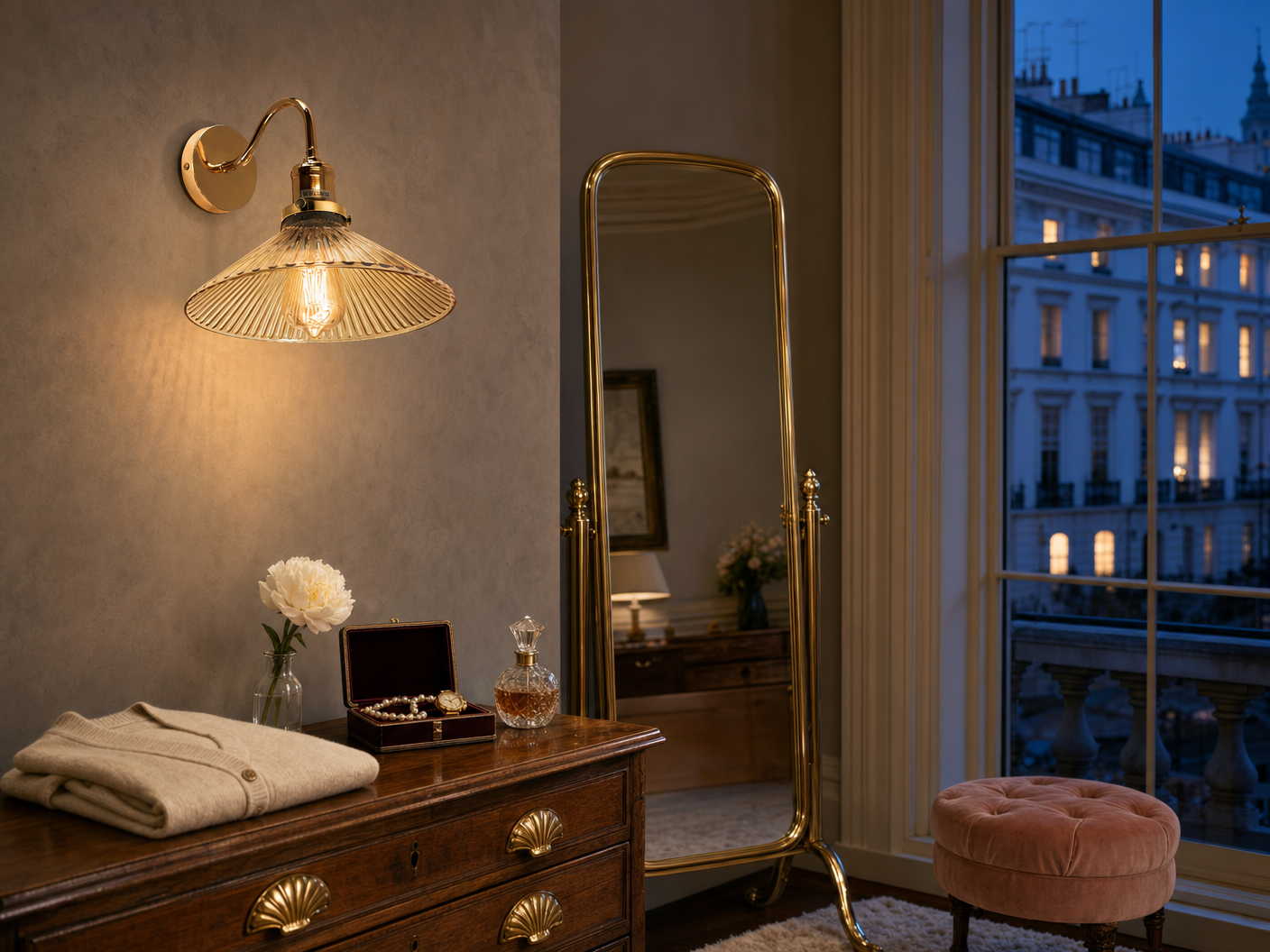 Belgravia amber-fluted-glass coolie-hat wall sconce in polished brass mounted on a Cornforth grey plaster wall in a townhouse master dressing room at blue-hour twilight, beside a tall brass-frame cheval mirror and antique walnut chest with brass shell-pull handles, sash window beyond