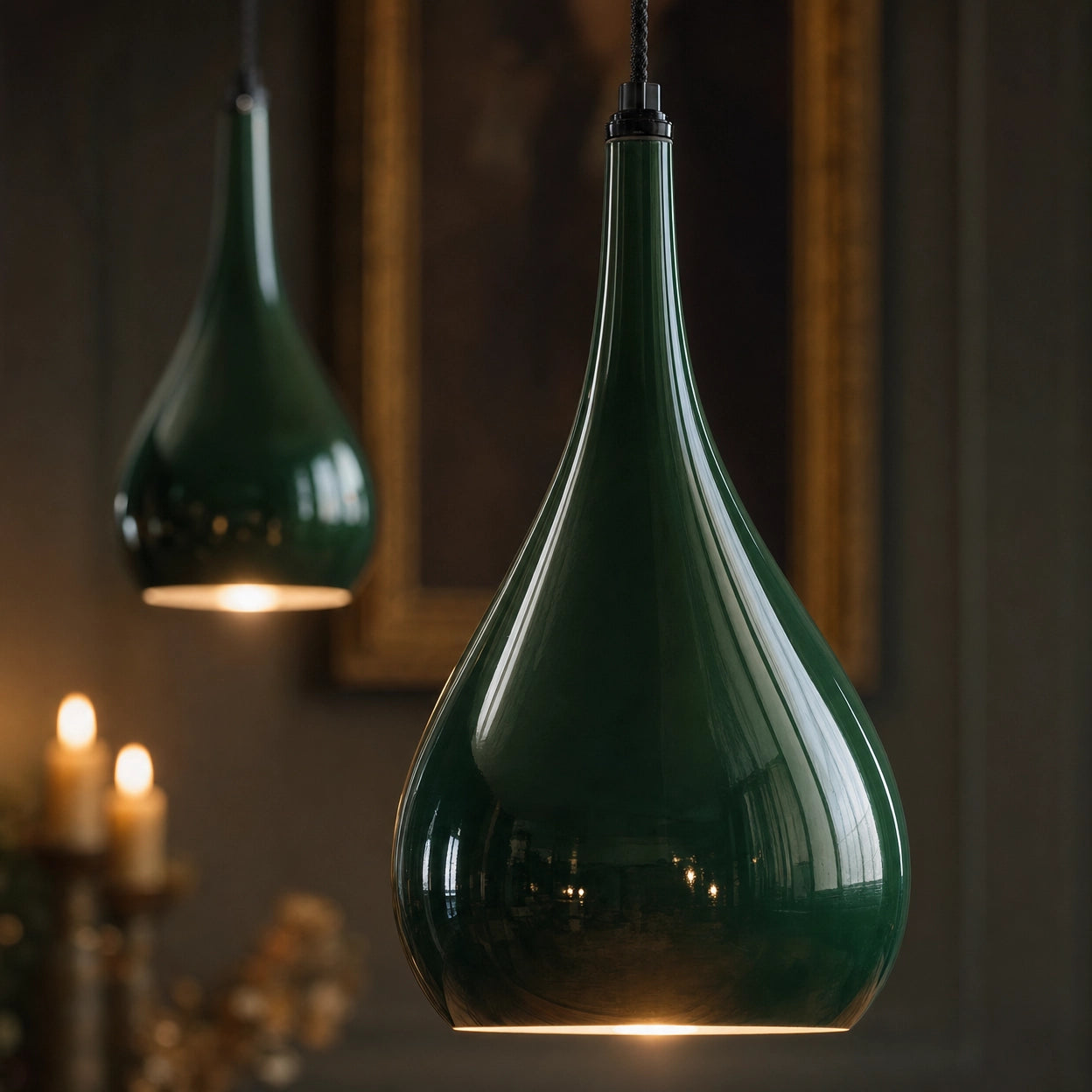 Detail of two Halcombe teardrop shades in glossy Studio Green enamel, candlelit interior beyond, showing the curved silhouette and surface finish