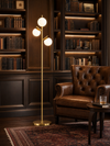 Kensington Gold Tone 3-Light Globe Tree Floor Lamp beside leather armchair in home library