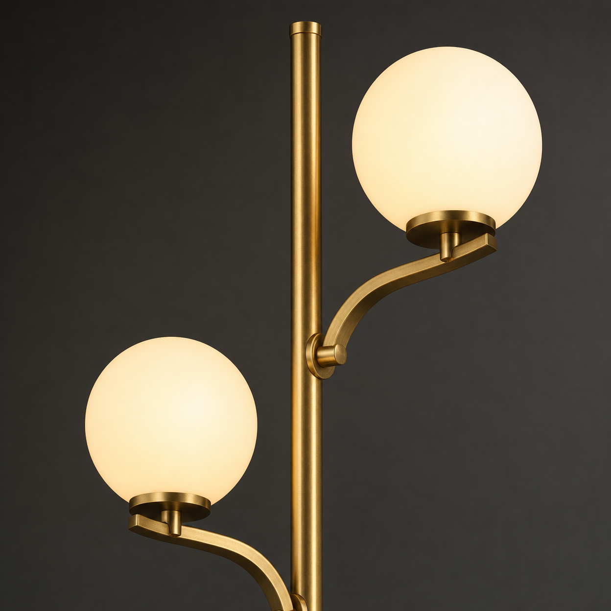 Close-up detail of Kensington gold metal arms and frosted glass globe shades