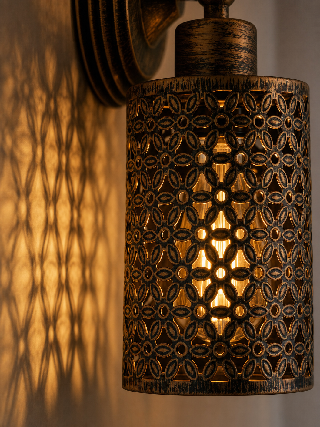Close-up detail of the Spitalfields wall sconce showing ornate perforated floral metalwork and warm amber light patterns